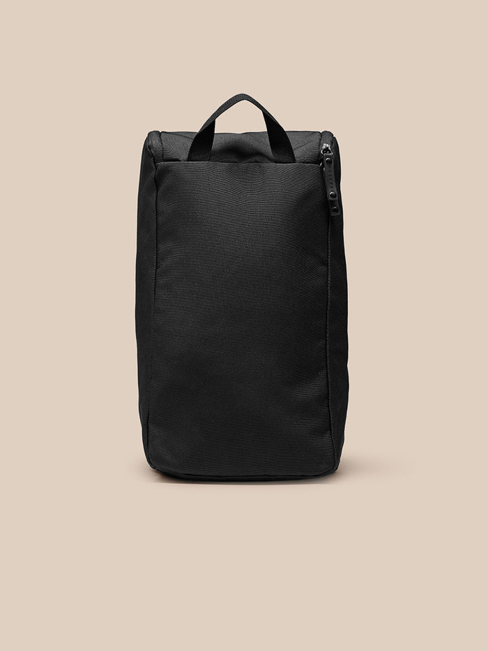 Black boot bag shown from the side with top handle, vertical zipper and metal eyelets at the base.