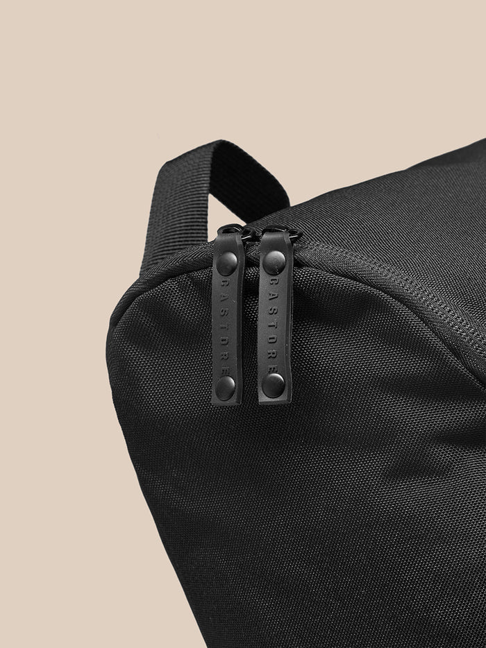 Close-up of black Castore boot bag showing twin zipper pulls and a top strap.