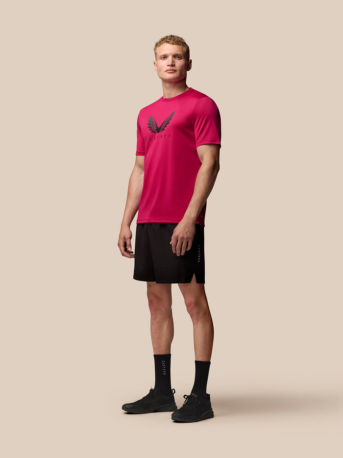 Full-body side view of a male model wearing pink Adapt Training T Shirt with wing graphic and black shorts.