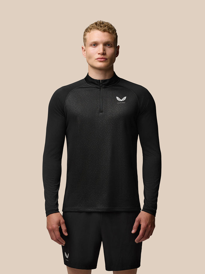 Front view of a male model wearing black Adapt Print 1/4 zip top with geometric pattern and chest logo