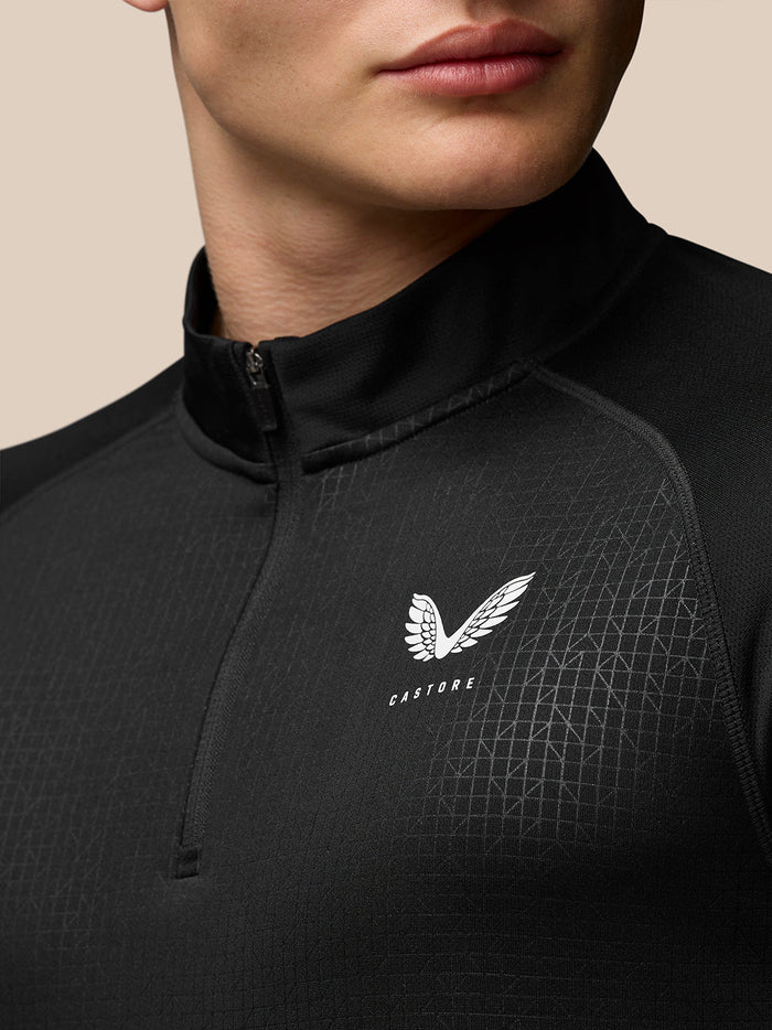 Close up of black Adapt quarter zip top with stand collar and all over geometric print, Castore logo on the chest