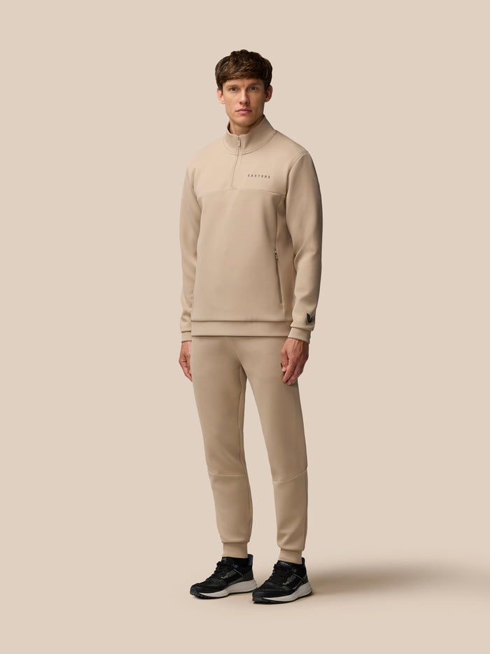 Male model wearing beige mushroom Flex Lifestyle joggers with matching zip top