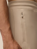Side view close-up of beige Flex Lifestyle Joggers highlighting the vertical zip pocket and Castore branding on the calf