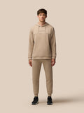 Male model wearing beige mushroom FLEX LIFESTYLE HOODIE with Castore wordmark on chest
