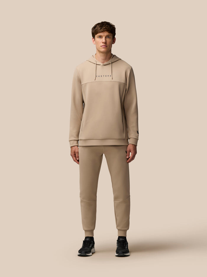 Male model wearing beige mushroom FLEX LIFESTYLE HOODIE with Castore wordmark on chest