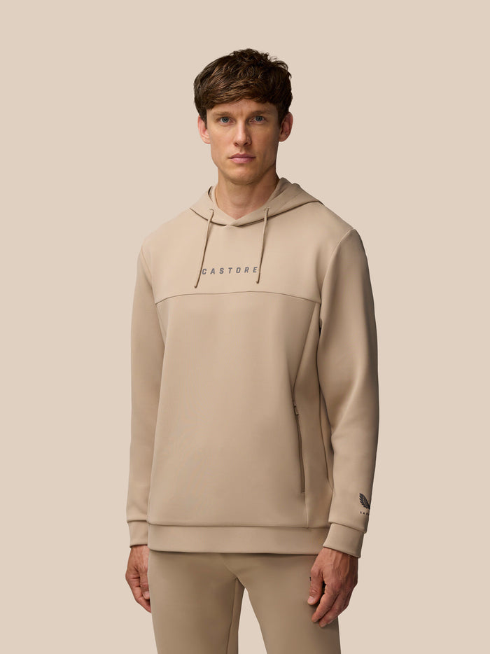 Front view of a man wearing mushroom Flex Lifestyle Hoodie with hood drawstrings and Castore wordmark on chest