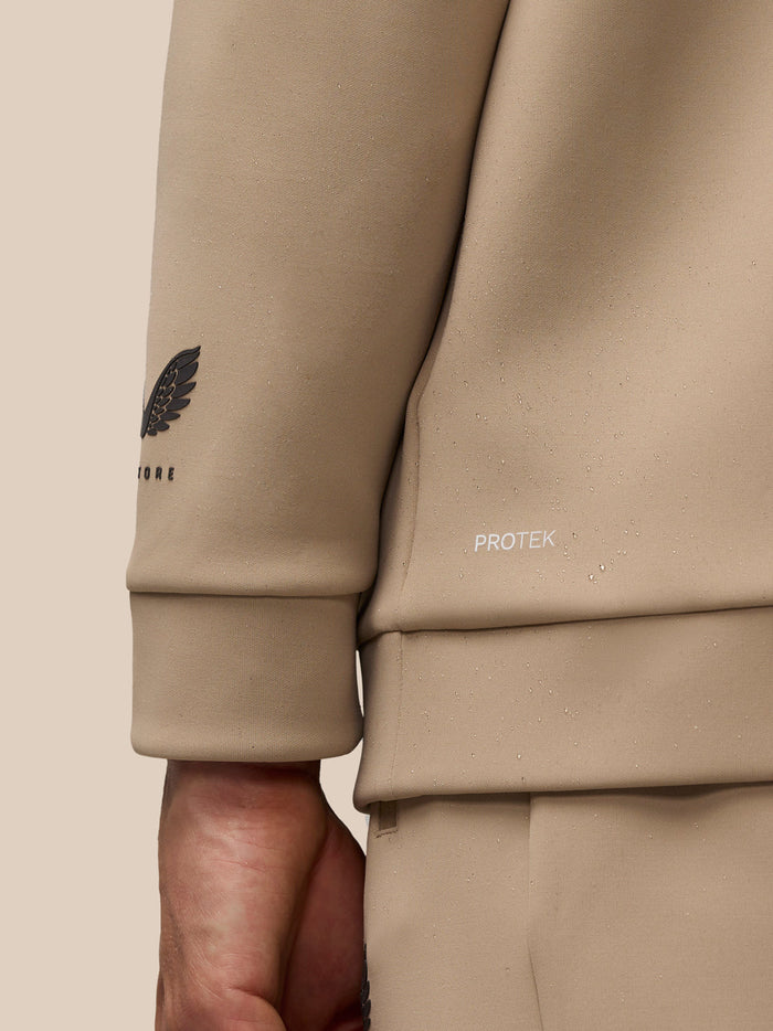Close-up of beige sleeve featuring ProTek logo and Castore wing emblem