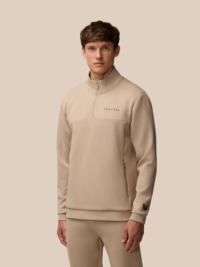 Male model wearing mushroom beige Flex Lifestyle 1/4 zip top with front center zipper and Castore logo on chest