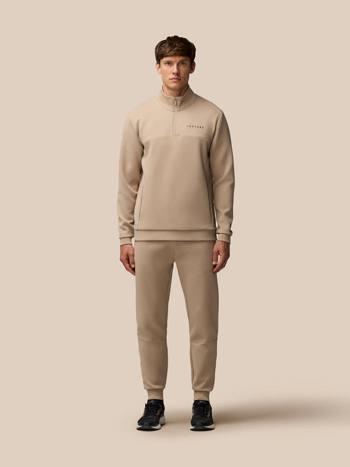 Male model in matching mushroom beige Flex Lifestyle scuba quarter zip top and joggers with zip pockets