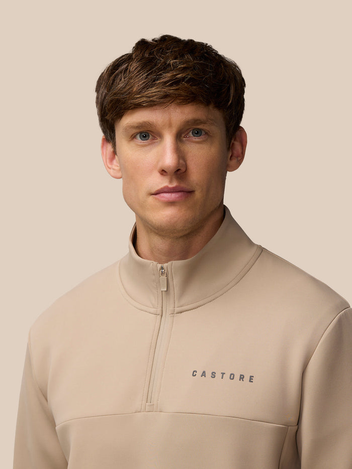Male model wearing mushroom gunmetal Flex Lifestyle 1/4 zip with Castore logo and zip pockets