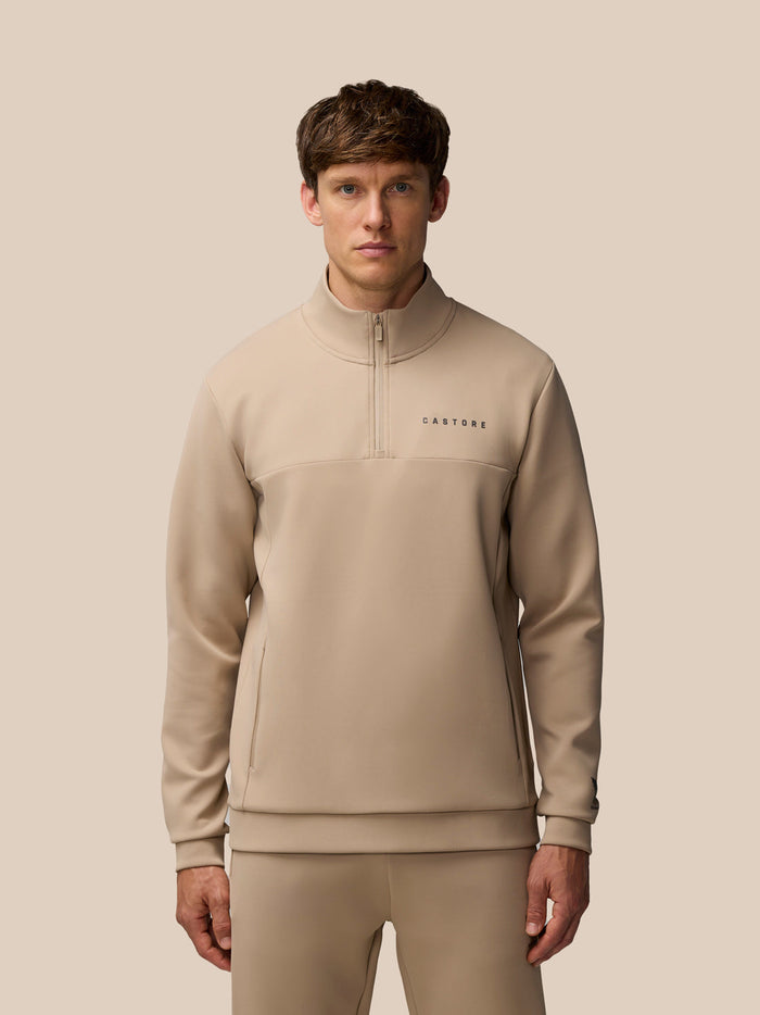 Front view of man wearing Flex Lifestyle 1/4 Zip top in mushroom gunmetal with Castore logo on left chest