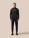 Full-body view of a male model in a black Castore tracksuit with a quarter-zip top and matching joggers