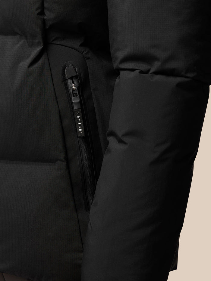 Close-up of a black puffer jacket pocket with a vertical zip and Castore branding on the zipper pull