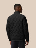 Back view of a man wearing a black padded jacket with a quilted chevron pattern and stand collar.