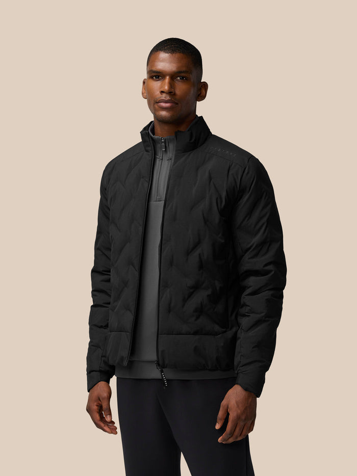 Male model in black padded jacket with zip front and high collar; Castore branding on left shoulder