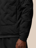 Close-up of black padded jacket fabric showing a subtle grid texture and sleeve seam.