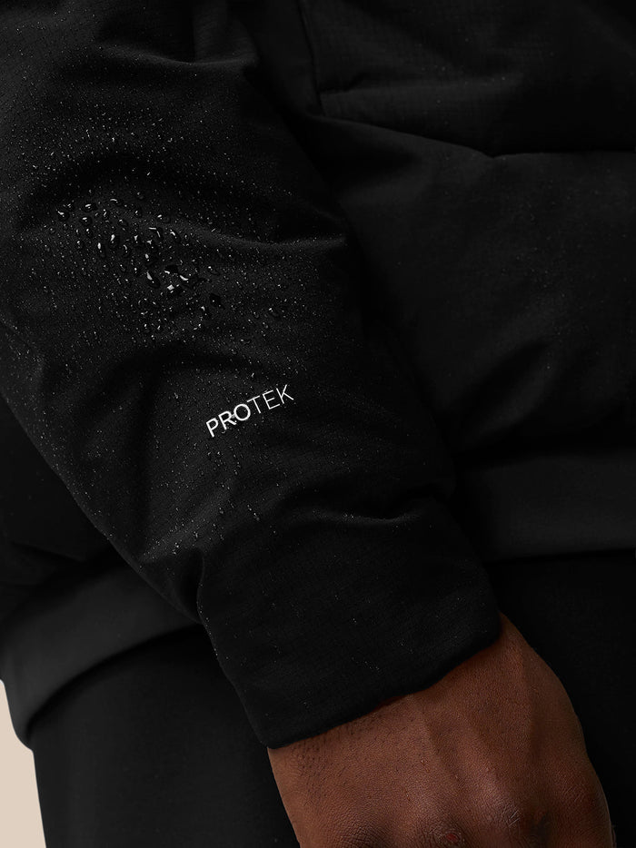 Close-up of a black padded jacket sleeve with Protek branding and water droplets.