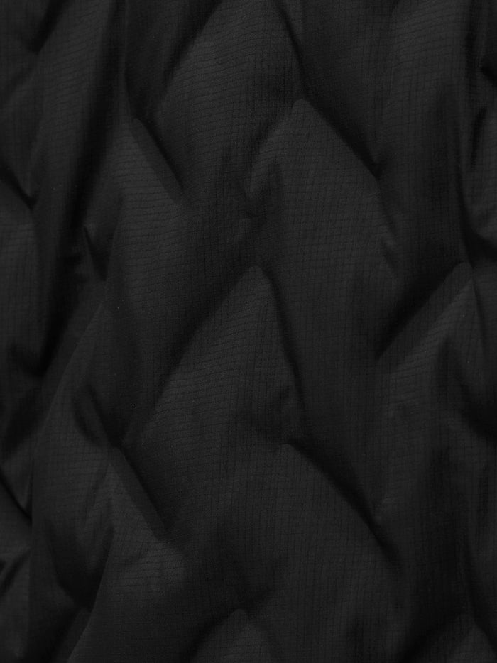 Close-up of black padded jacket fabric with subtle grid texture.