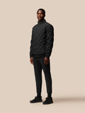 Male model wearing a black padded jacket with stand collar and full front zipper.