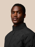 Black padded jacket close up with stand collar and Castore branding on the shoulder.