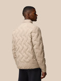 Rear three quarter view of male model in mushroom padded jacket showing diamond quilt and relaxed fit