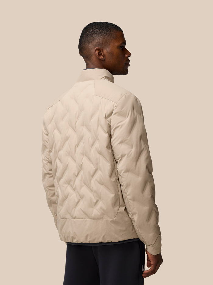 Rear three quarter view of male model in mushroom padded jacket showing diamond quilt and relaxed fit