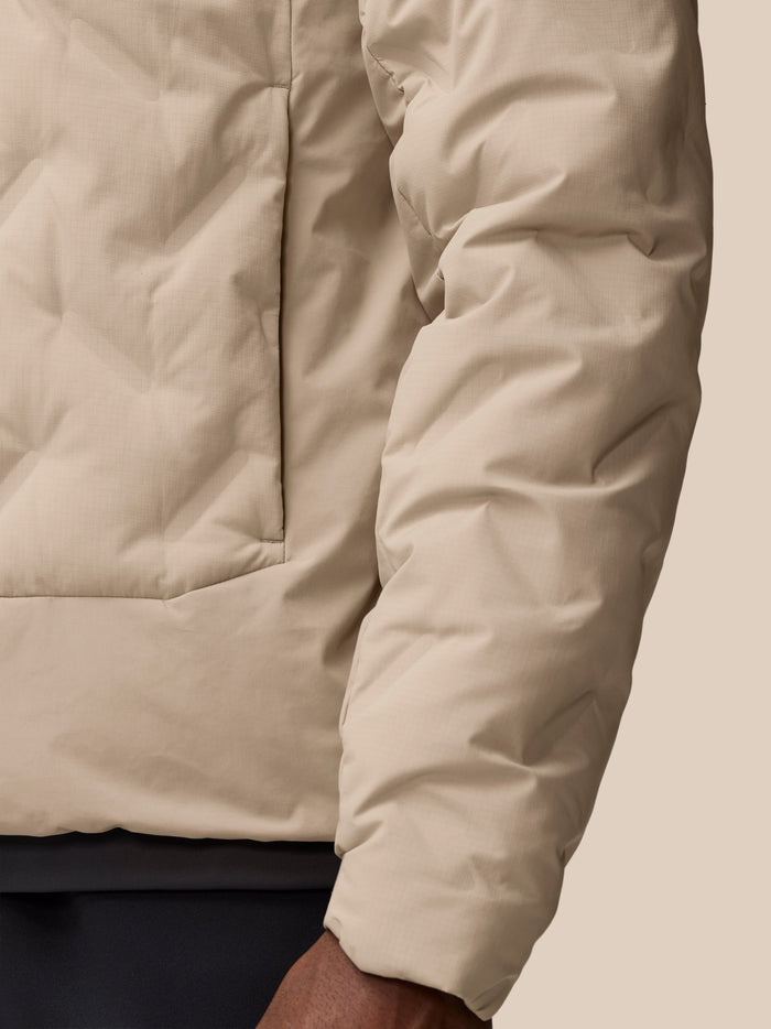 Close up of beige padded jacket sleeve with water droplets to show water resistance