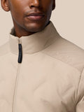 Beige padded jacket shown at a close range with front zipper and chest logo.