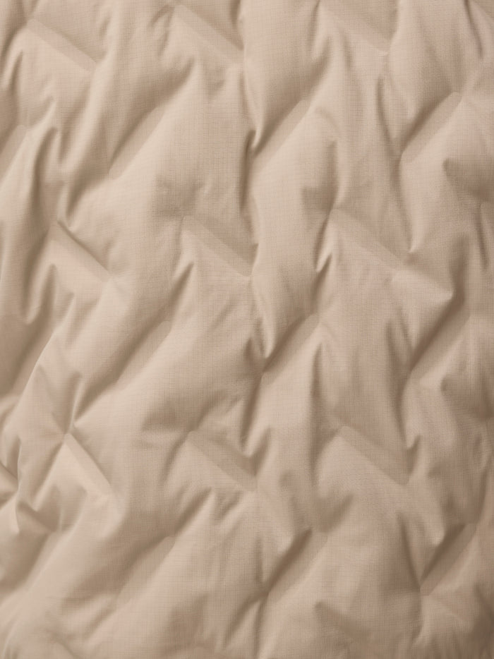 Beige fabric close up with a fine grid texture from the mushroom padded jacket.