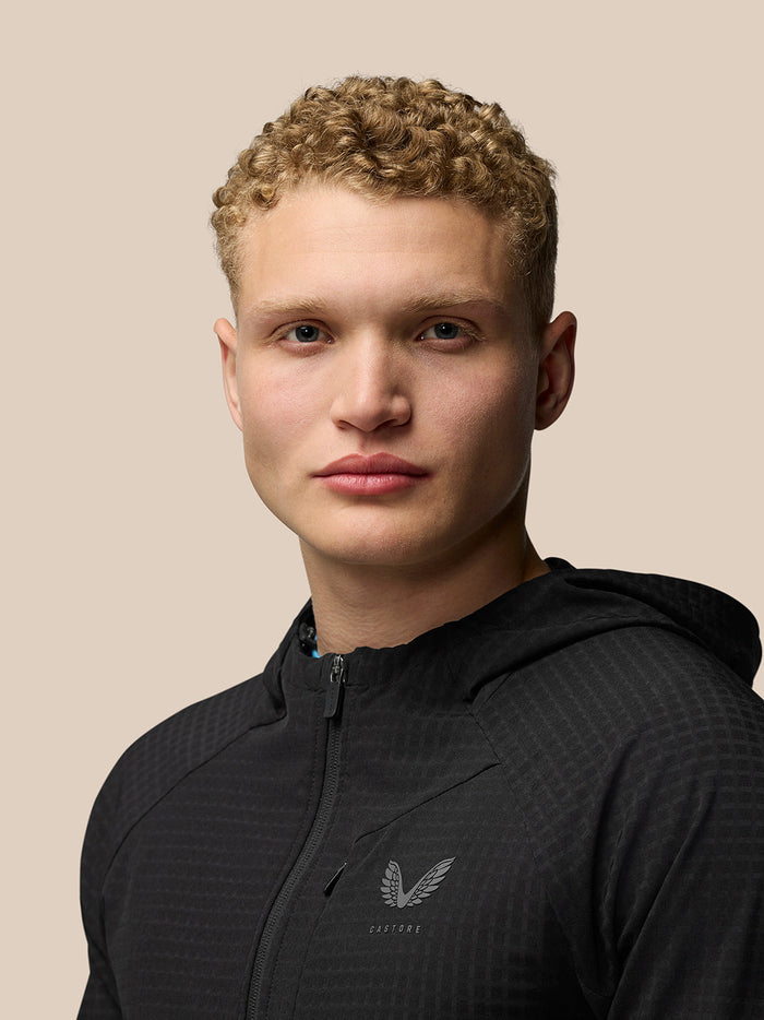 Portrait of a model wearing a black FLEX WINTERISED JACKET against a beige background