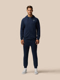 Man wearing a navy zip hoodie with drawstrings and Castore logo on the chest.