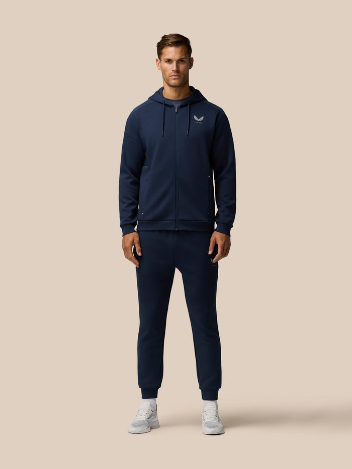 Man wearing a navy zip hoodie with drawstrings and Castore logo on the chest.