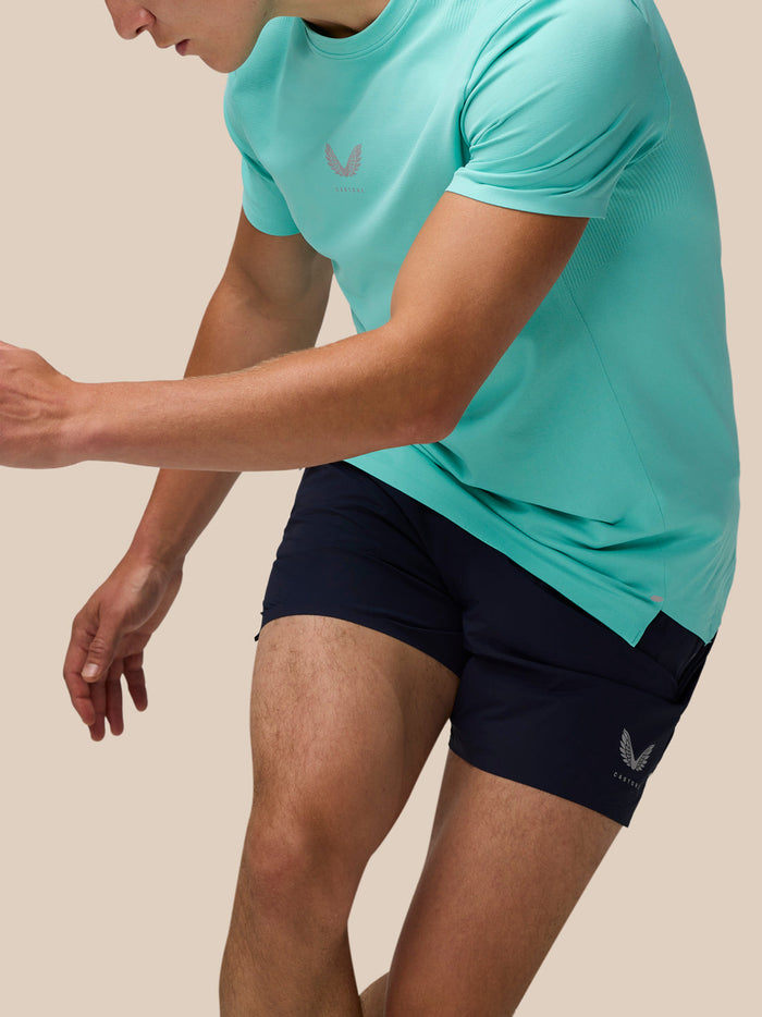 Front view of a man in light aqua Zone Training T-Shirt with a small chest logo and navy shorts