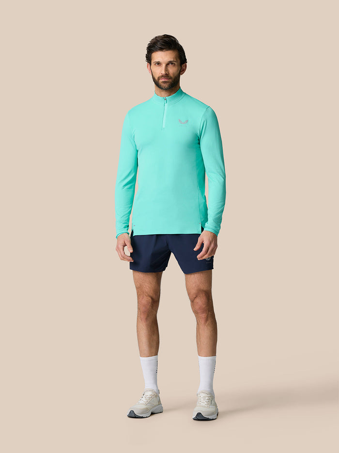 Male model wearing light aqua Zone Training 1/4 zip top with high neck and navy shorts.