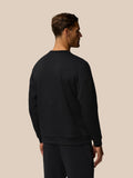 Back view of a man wearing a black Travel Lifestyle Sweatshirt with dropped shoulder seams.