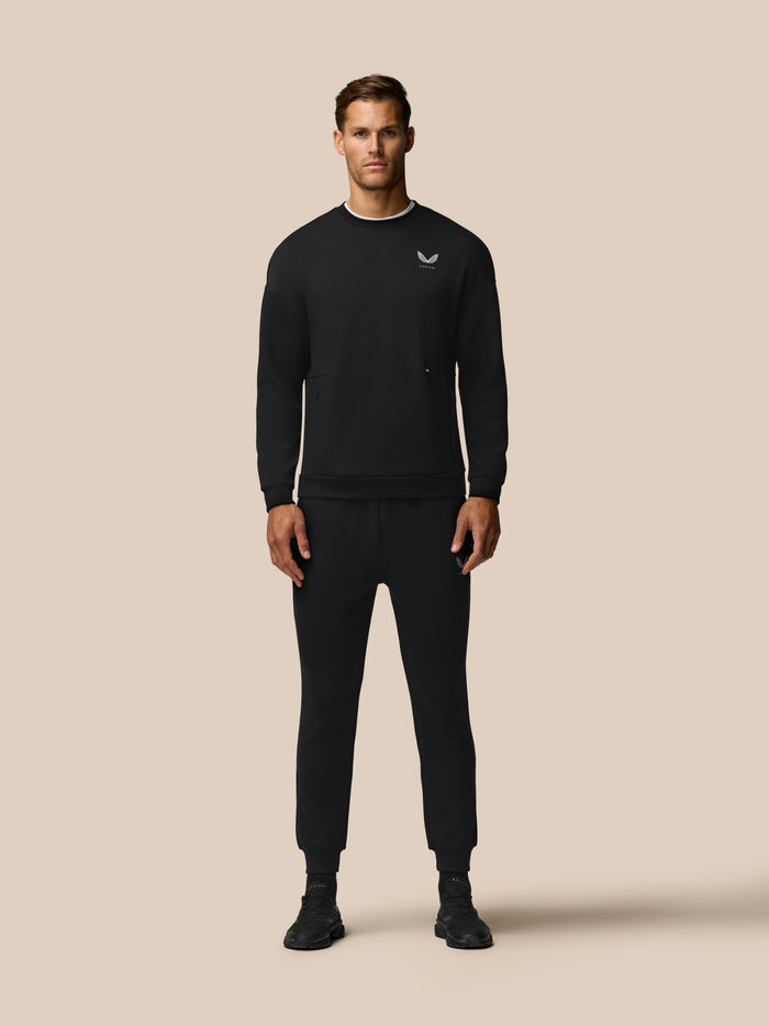 Front view of a man wearing a black Travel Lifestyle Sweatshirt with a small chest logo.