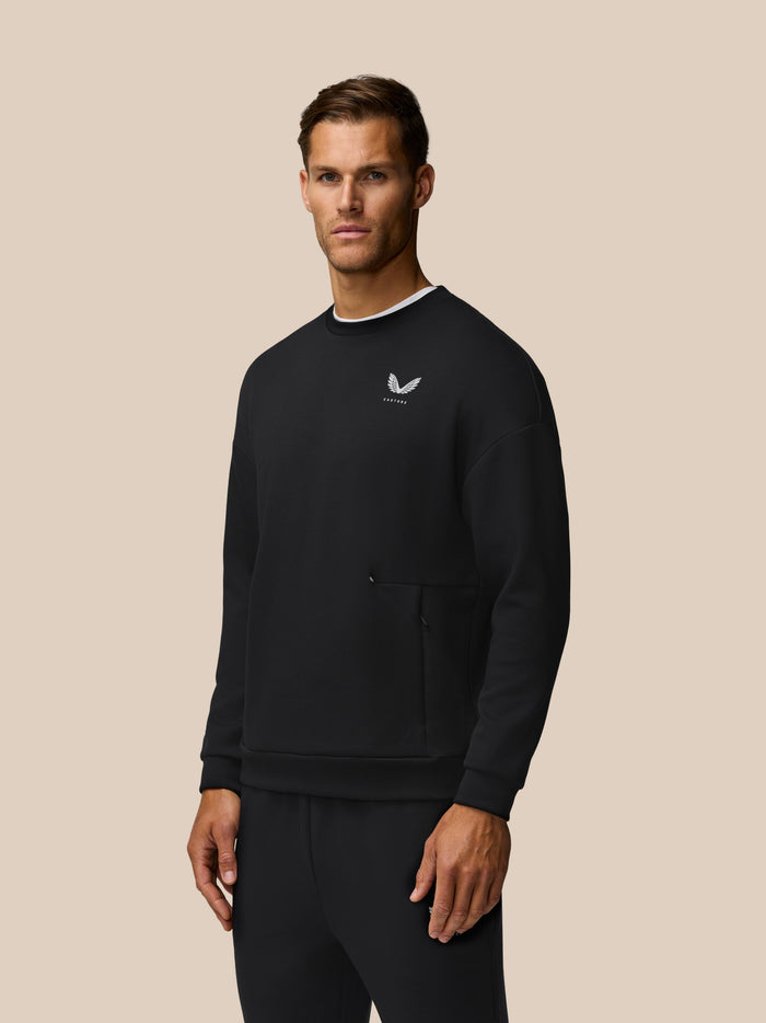 Man wearing black travel lifestyle crew neck sweatshirt with white neck trim and small chest logo
