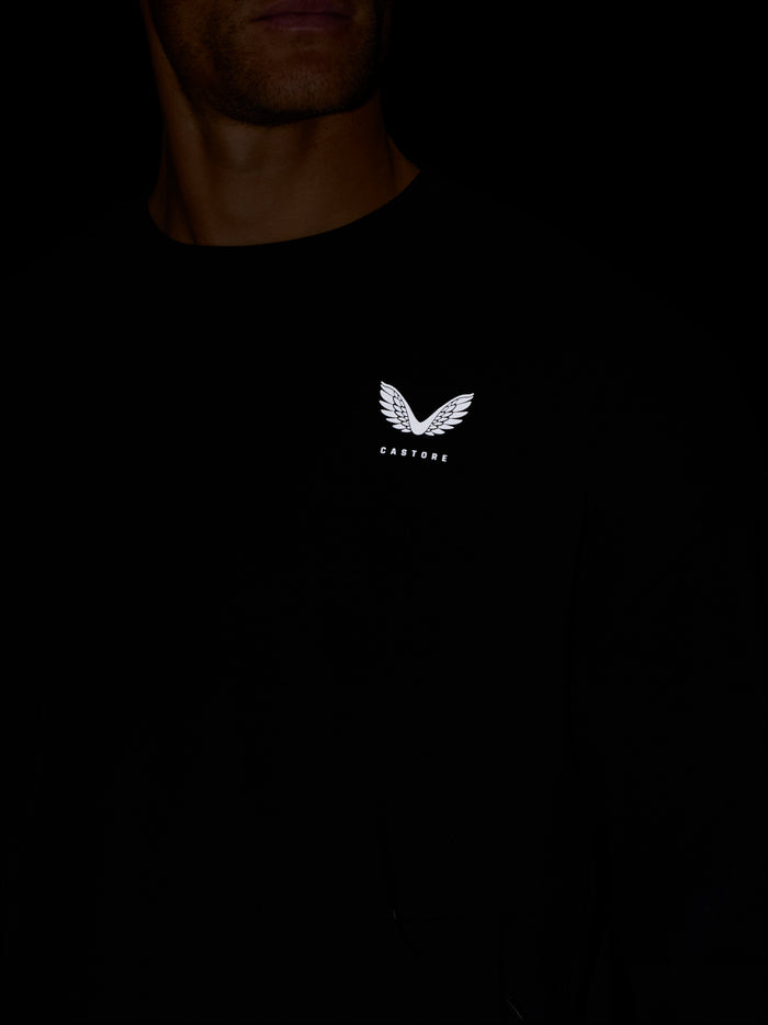 Person wearing black travel lifestyle sweatshirt with white wing logo on the chest.