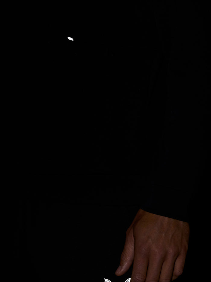 White wing logo on black sweatshirt with a hand in frame.