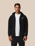 Front view of a man in a black travel zip hoodie with hood down and Castore logo on chest