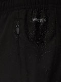 Close-up of black Apex Training shorts fabric with a ProTek zipper pull and water droplets.