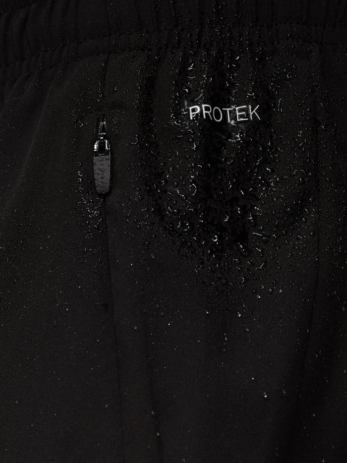 Close-up of black Apex Training shorts fabric with a ProTek zipper pull and water droplets.