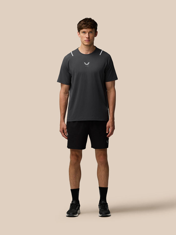 Man wearing dark gray Apex short sleeve T shirt with reflective shoulder accents and Castore logo on chest, black shorts