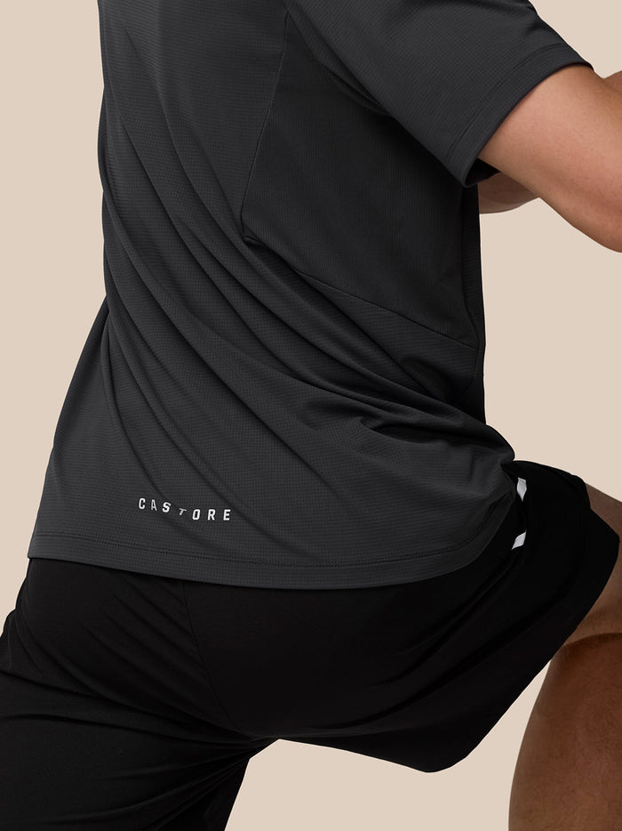 Close-up of back hem with Castore branding on the dark gray Apex T shirt and textured knit fabric