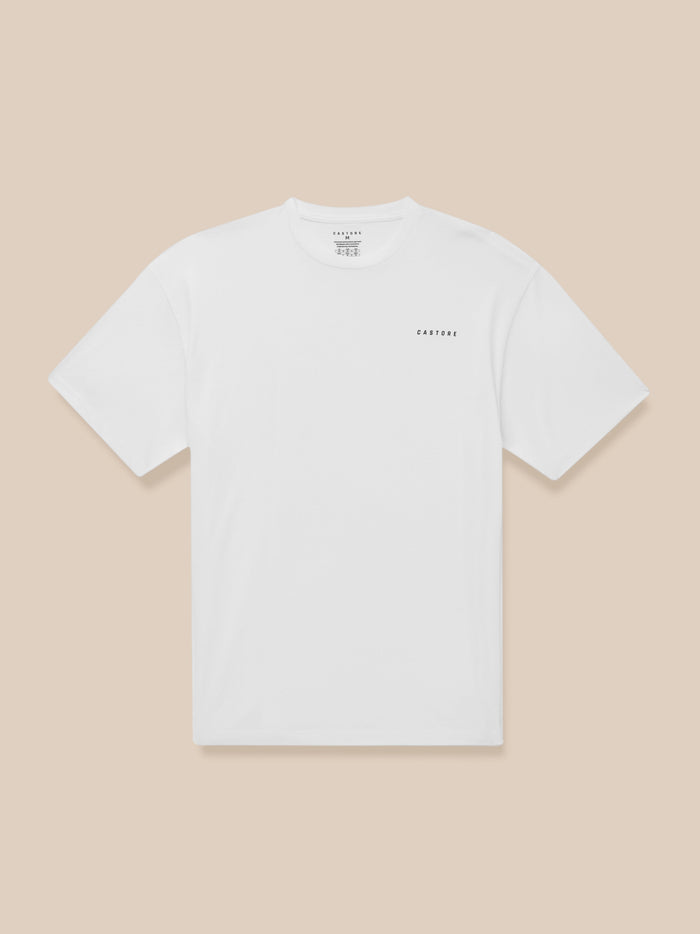 White short sleeve T shirt with small black CASTORE logo on the chest against a beige background