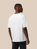 Rear view of a male model in a white oversized T shirt showing the back and relaxed fit.