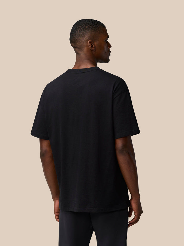 Rear view of a man wearing a black short sleeve T shirt with a round neckline