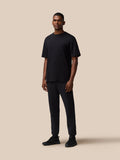 Full body view of a man wearing a black T shirt and matching joggers with black sneakers