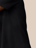 Close-up of a black Flex Cotton T-Shirt sleeve and chest with Castore branding on a beige background