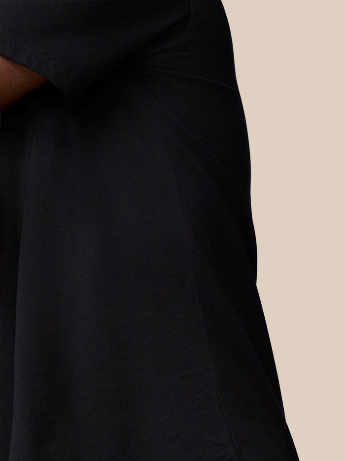 Close-up of a black Flex Cotton T-Shirt sleeve and chest with Castore branding on a beige background